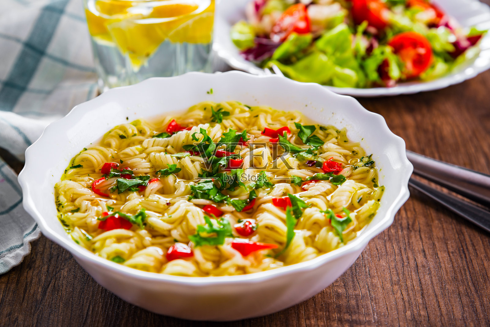 白碗里的方便面放在木桌的背景上，盘子里有蔬菜沙拉照片摄影图片