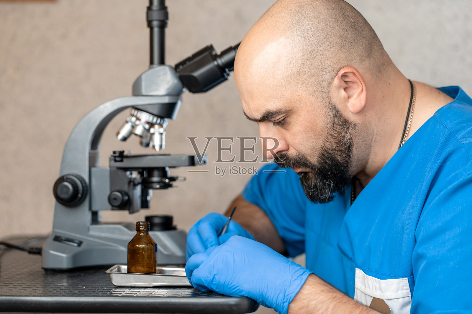 男性实验室助理，在显微镜下检查生物材料样本。照片摄影图片