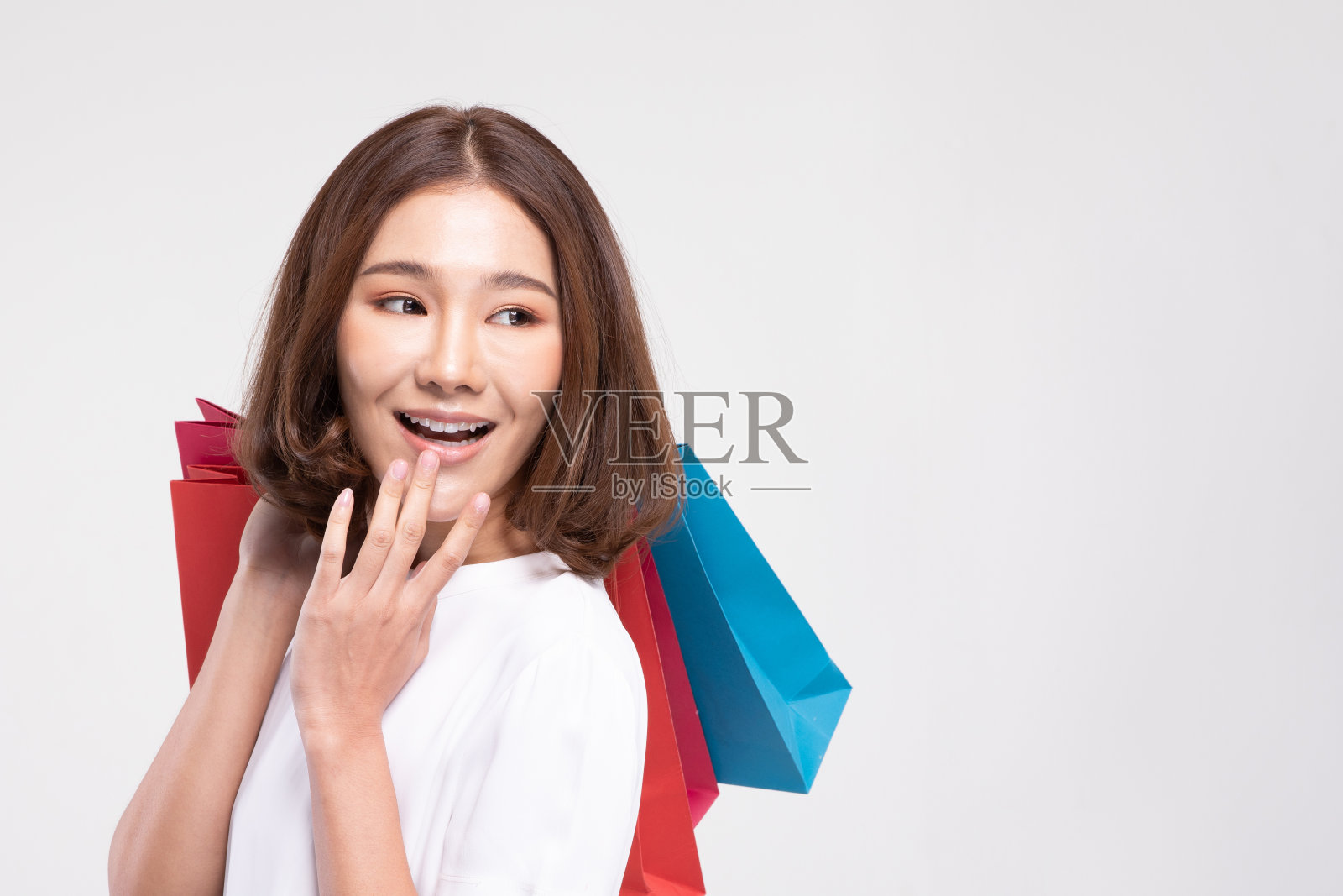 购物亚洲女人的短发微笑和拿着购物袋，快乐和幸福的情感，享受购物在黑色星期五的销售，孤立在灰色的背景，购物概念照片摄影图片