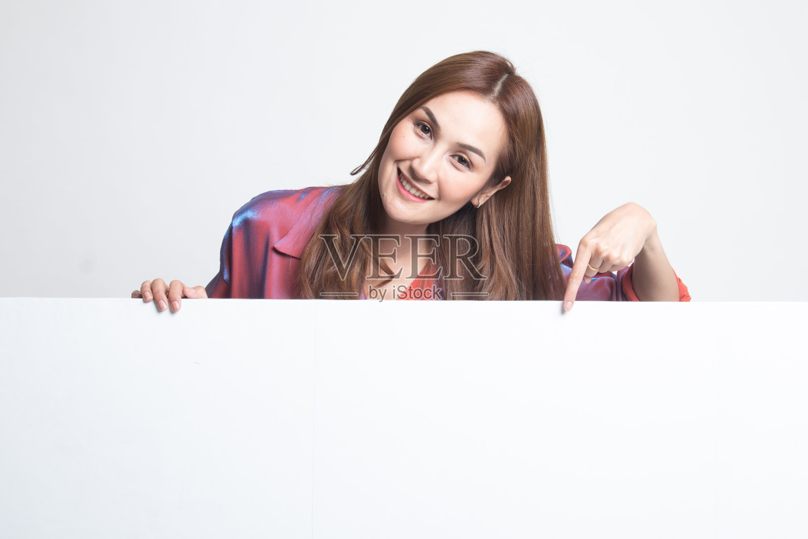 年轻的亚洲女子指着一个空白的标志。照片摄影图片