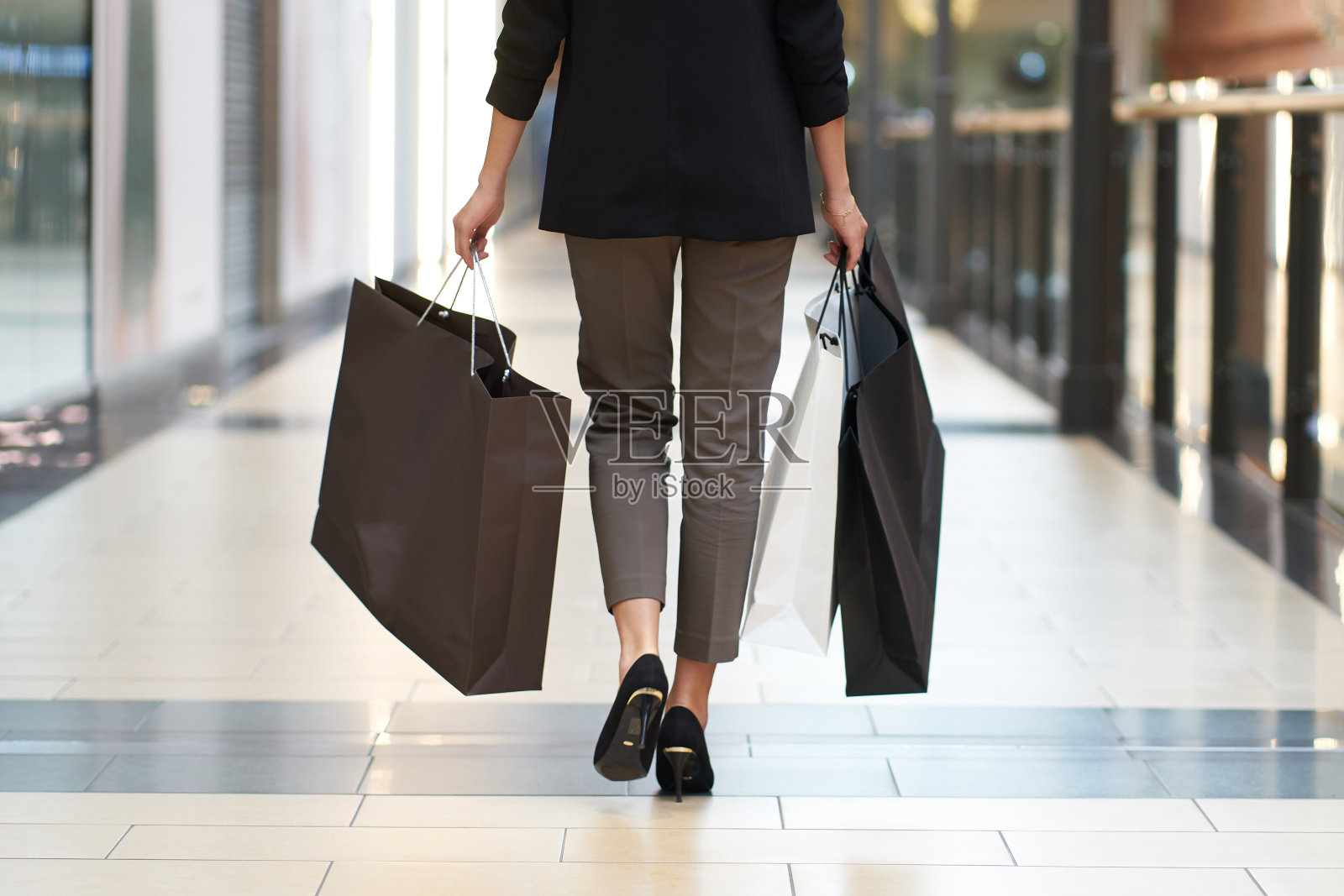 黑色星期五，时尚的女人穿着时髦的衣服，在商店背景上手提购物袋，背面视角照片摄影图片