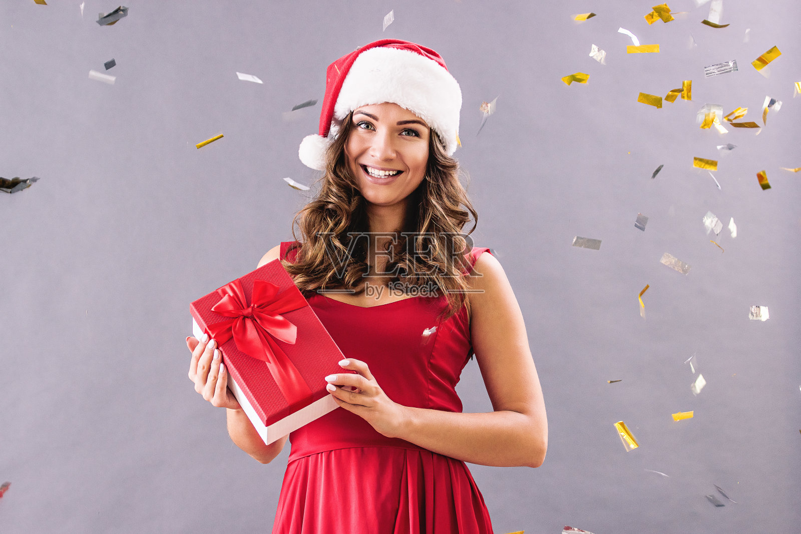 戴圣诞帽的快乐漂亮女人手捧礼物照片摄影图片