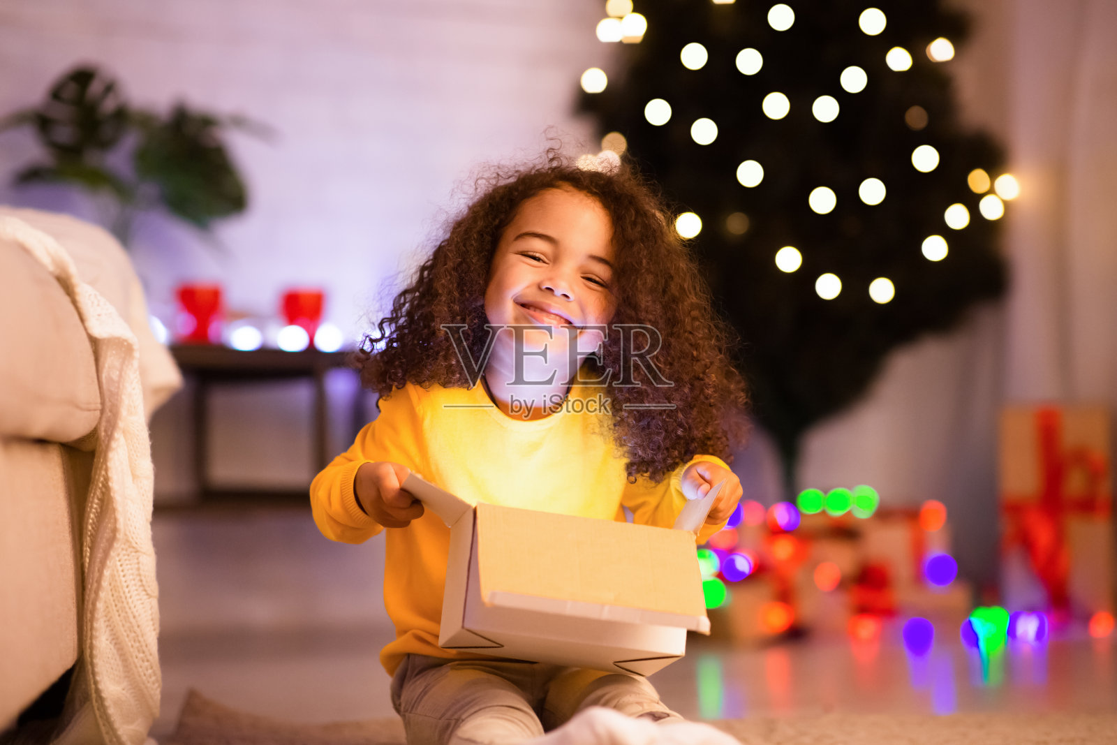 快乐的非洲裔儿童在圣诞树旁打开礼物照片摄影图片