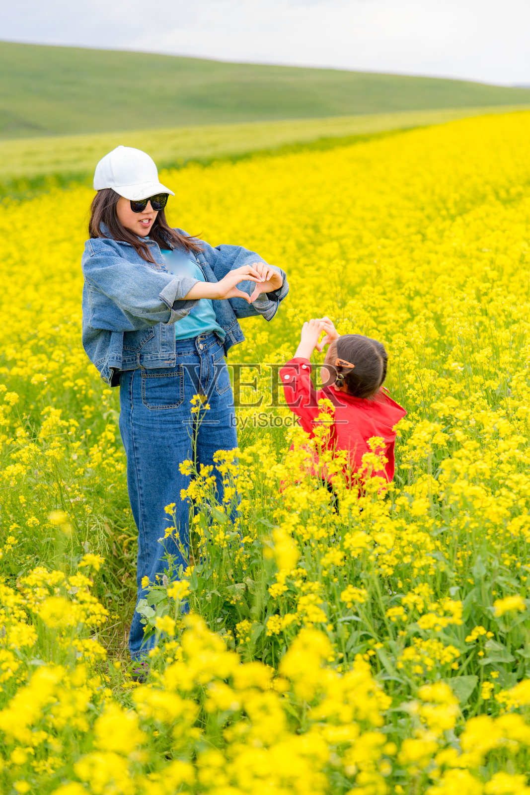 两姐妹在油菜花中嬉戏照片摄影图片