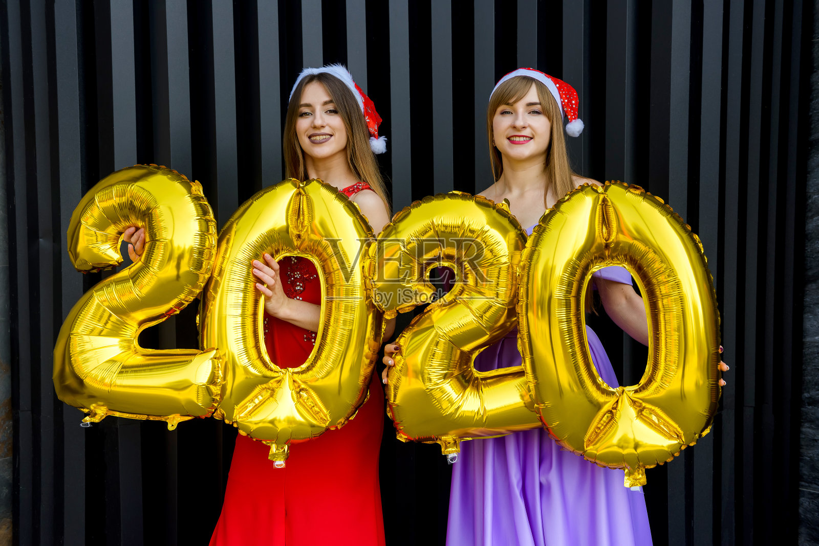 两个快乐的女孩在圣诞服装与金色数字气球摆姿势的肖像2020照片摄影图片