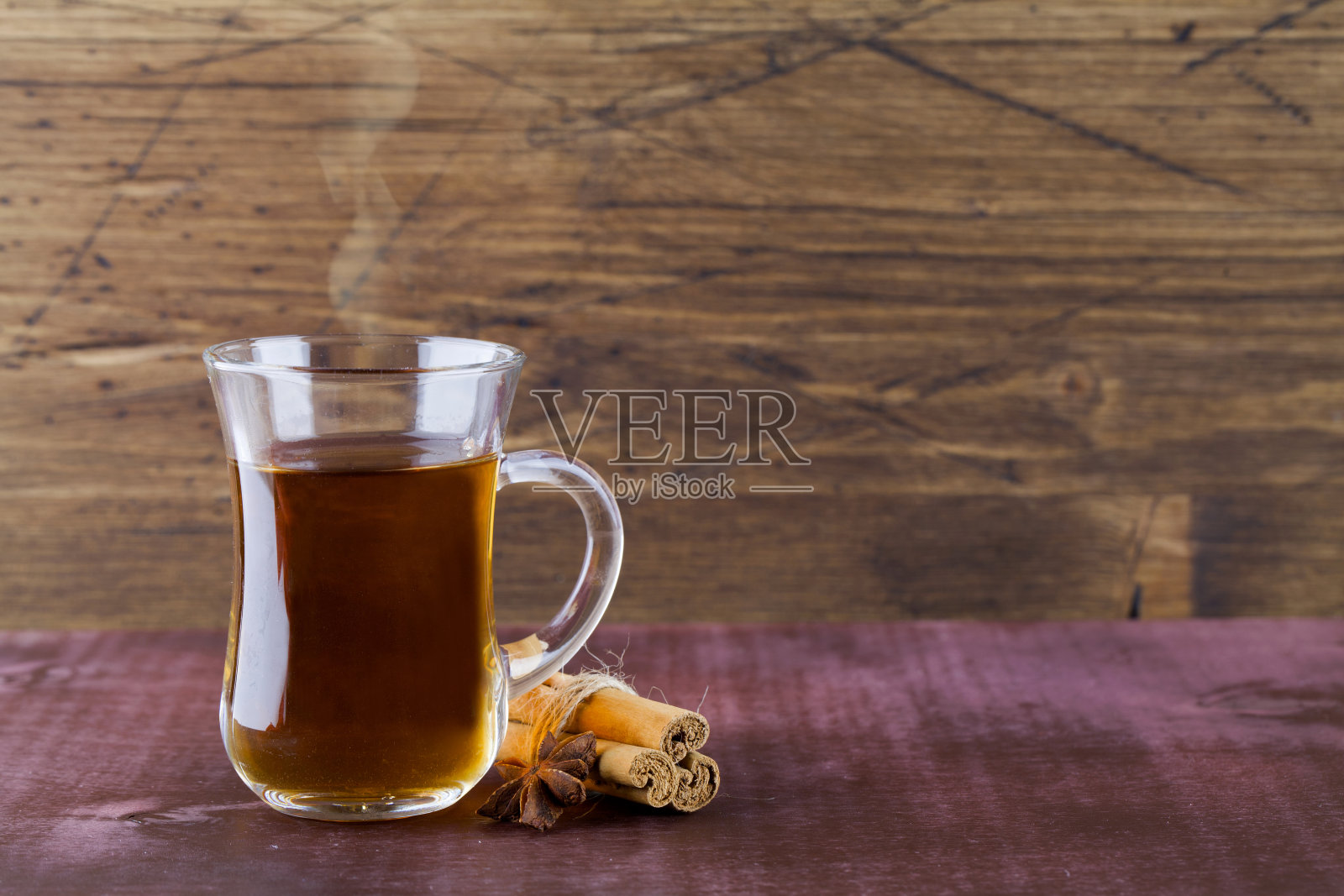 玻璃杯中的热茶，以肉桂木为背景。照片摄影图片