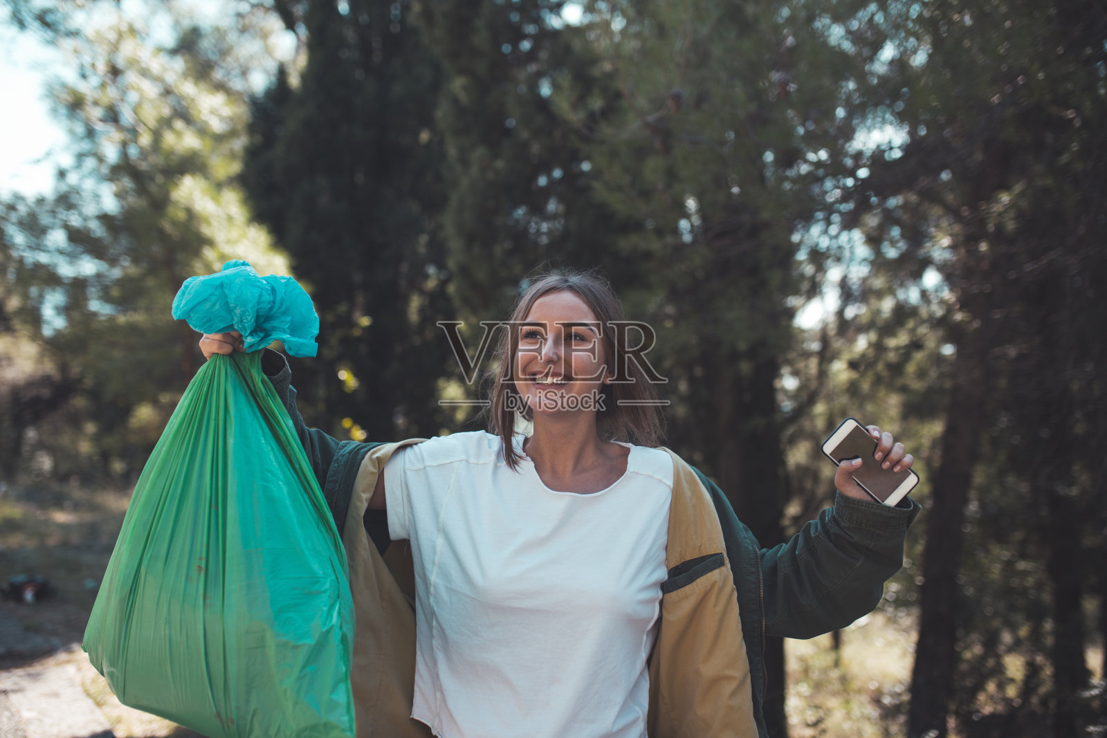 年轻的妇女志愿者清理森林中的塑料垃圾照片摄影图片