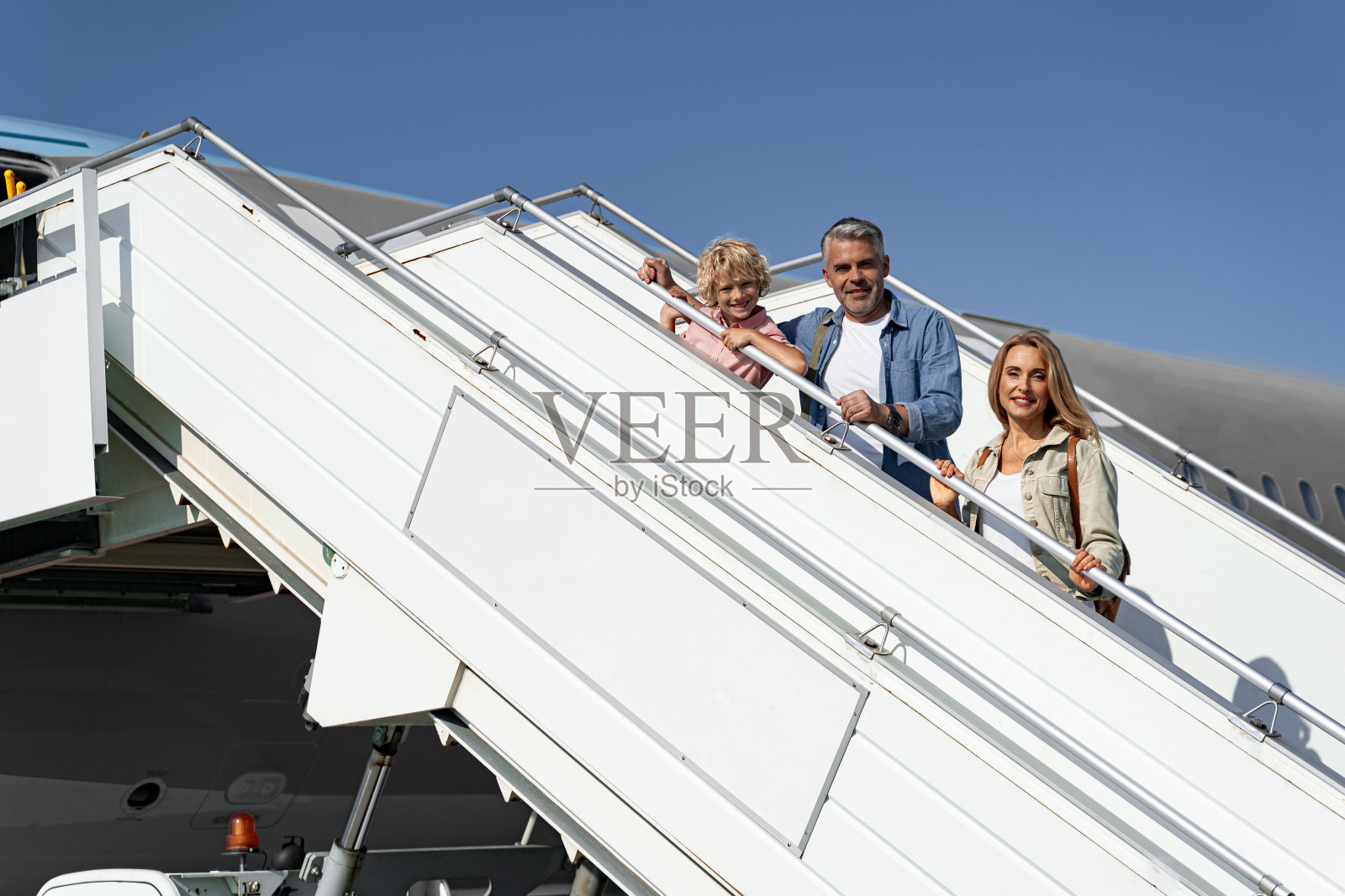 幸福的家庭在飞机旁对着镜头摆姿势照片摄影图片