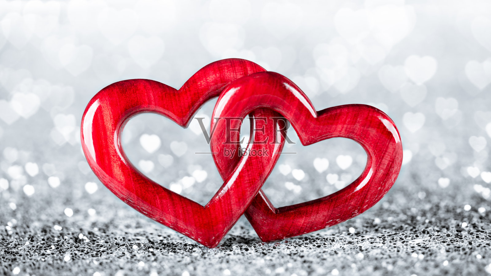 银色闪光上的两个红色木制连锁心照片摄影图片