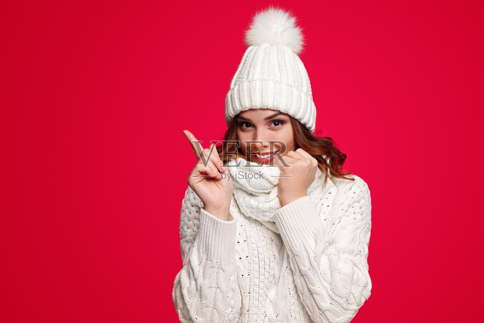 微笑的女人在温暖的衣服指着空照片摄影图片