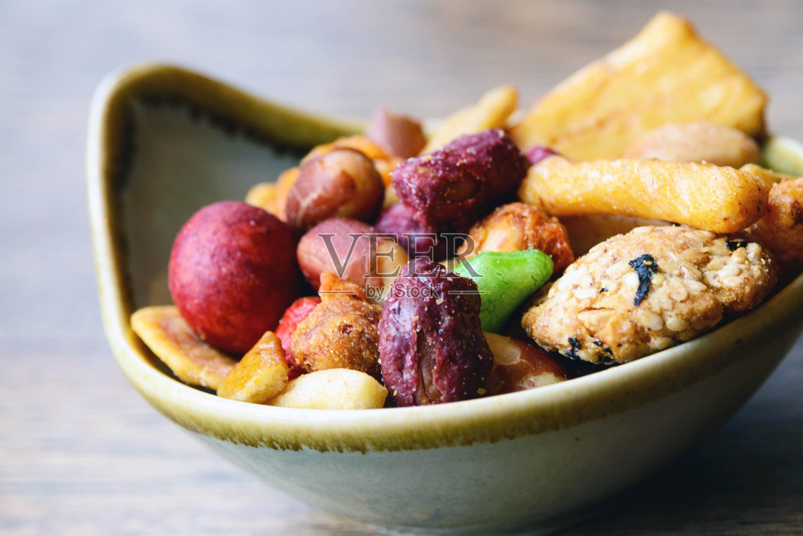 用盐和香料调味的坚果和饼干放在木桌上的一个小盘子里。伟大的啤酒吃零食。辣的小吃。照片摄影图片