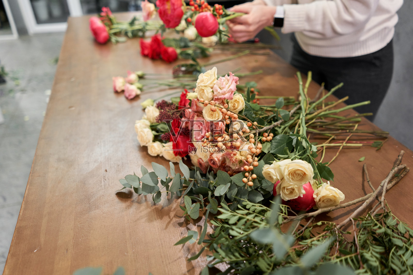 花艺师一步一步地创作红色混合花束。鲜花配送。欧洲花店概念。照片摄影图片