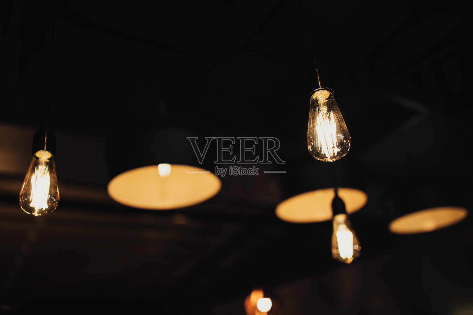 复古豪华室内模糊或散焦照明装饰在咖啡馆。老式的灯泡。餐厅酒吧室内照明设计。酒窖里酒瓶前的老式灯泡照片摄影图片