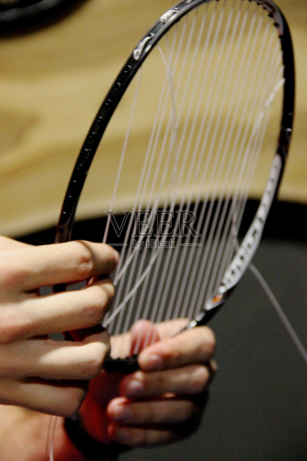 男人修理羽毛球拍，调整球拍弦线照片摄影图片