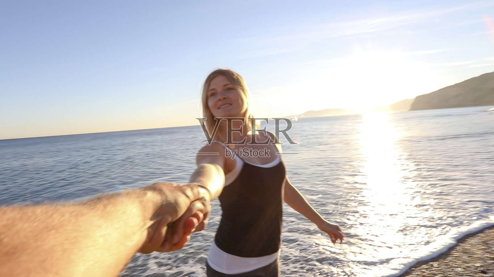 日出时，朋友们手牵着手在海滩上跑照片摄影图片