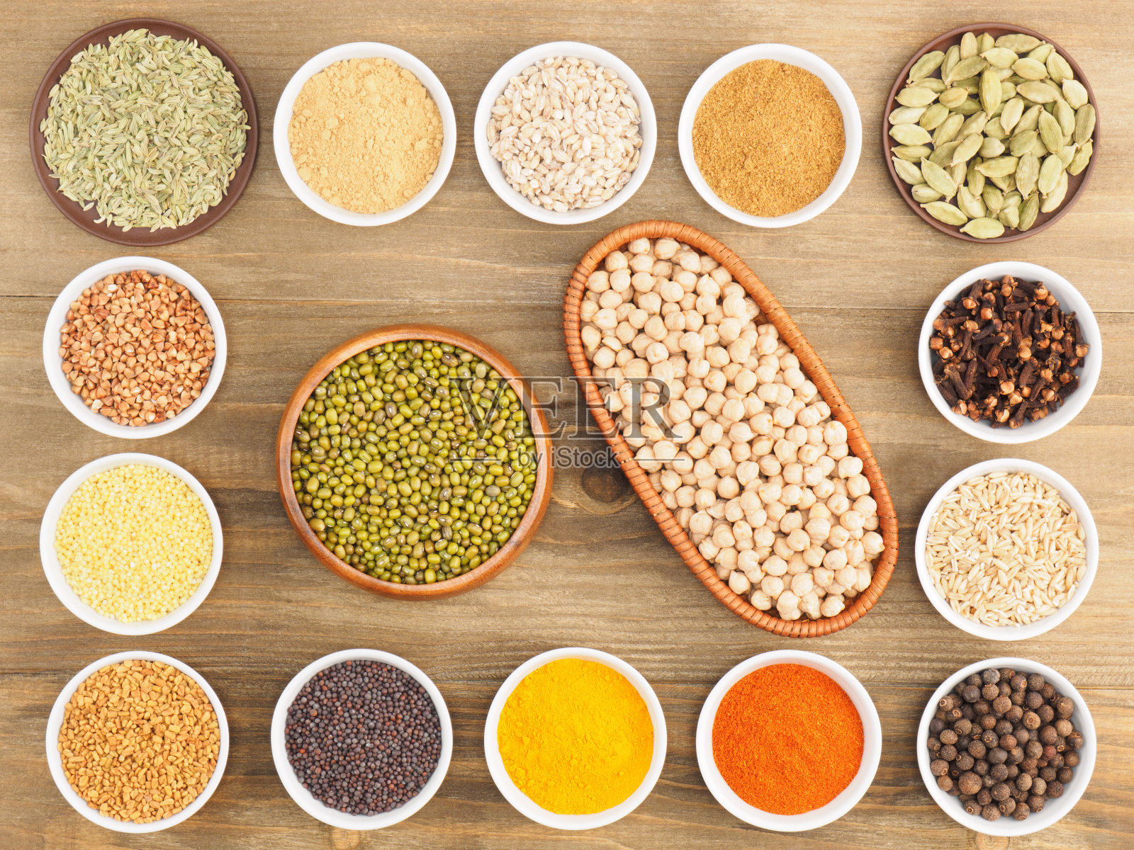 荞麦，燕麦，绿豆，鹰嘴豆，小米，绿豆蔻，多香果，干姜，辣椒，胡芦巴，姜黄，丁香，马沙拉，芥末种子在棕色的木质背景上。印度烹饪，阿育吠陀，自然疗法的概念照片摄影图片