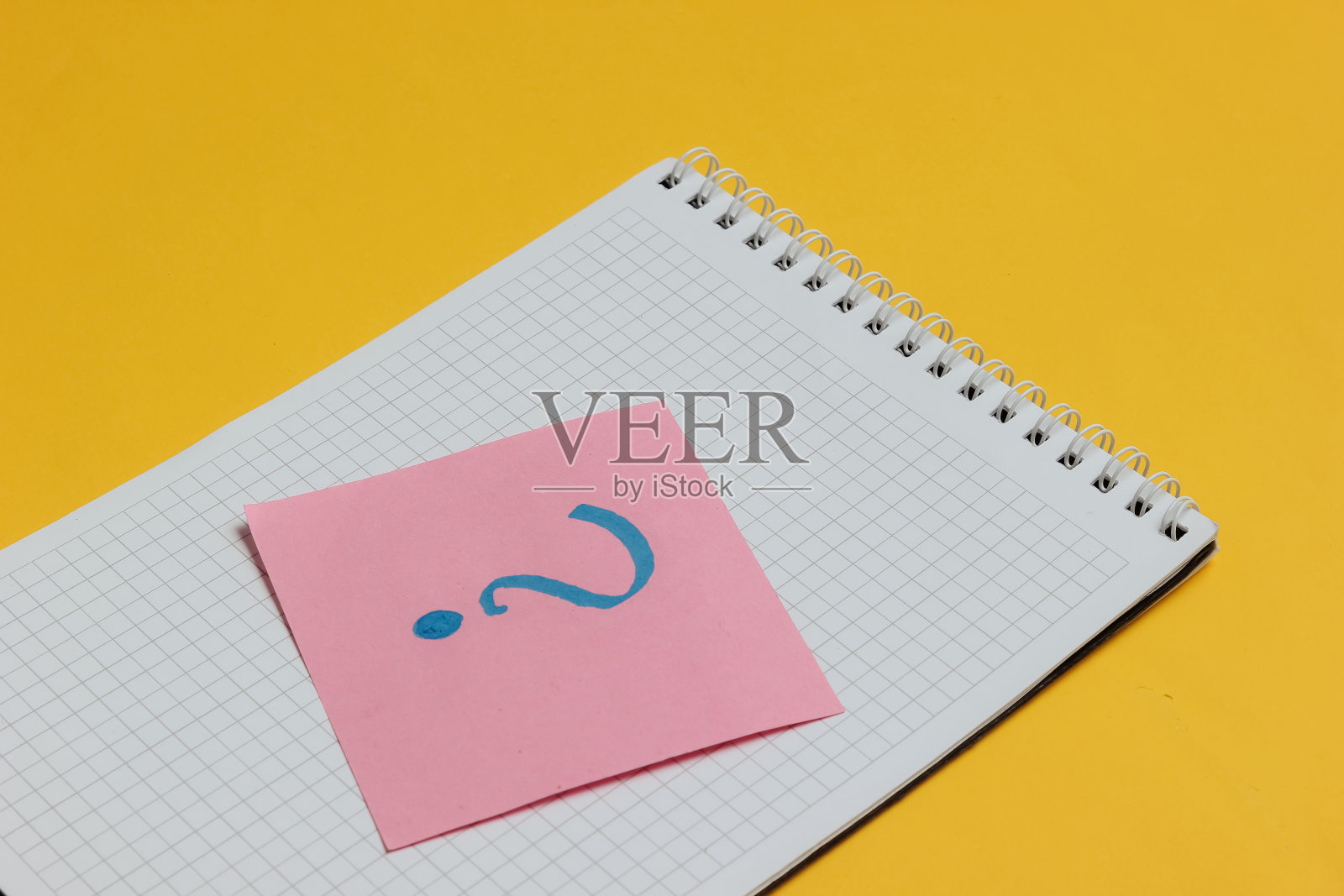 黄色背景上带问号的记事本和便笺纸。照片摄影图片