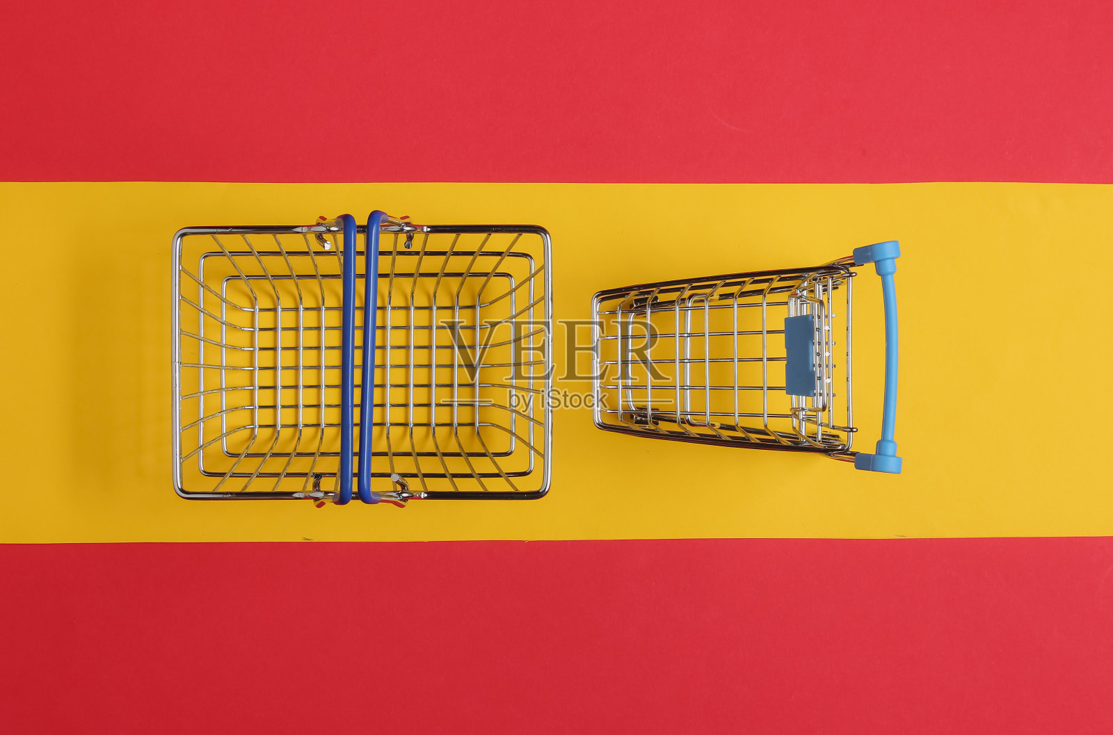 简约的购物理念。红黄背景的购物篮和手推车。俯视图照片摄影图片