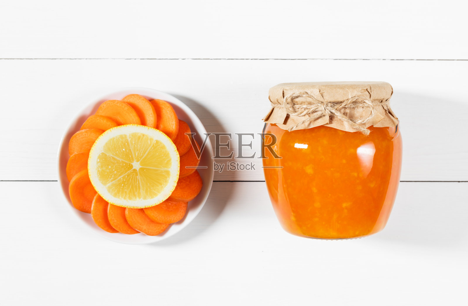 美味的自制柠檬胡萝卜果酱装在玻璃罐中，白色的木制背景。照片摄影图片