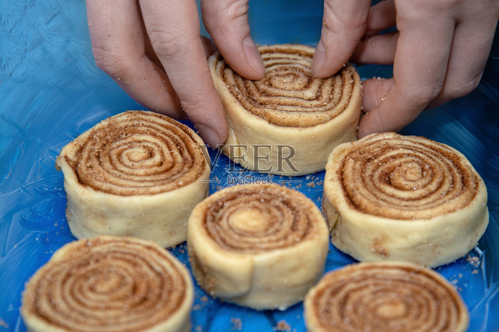 肉桂卷放在一个蓝色透明的烤盘里。照片摄影图片