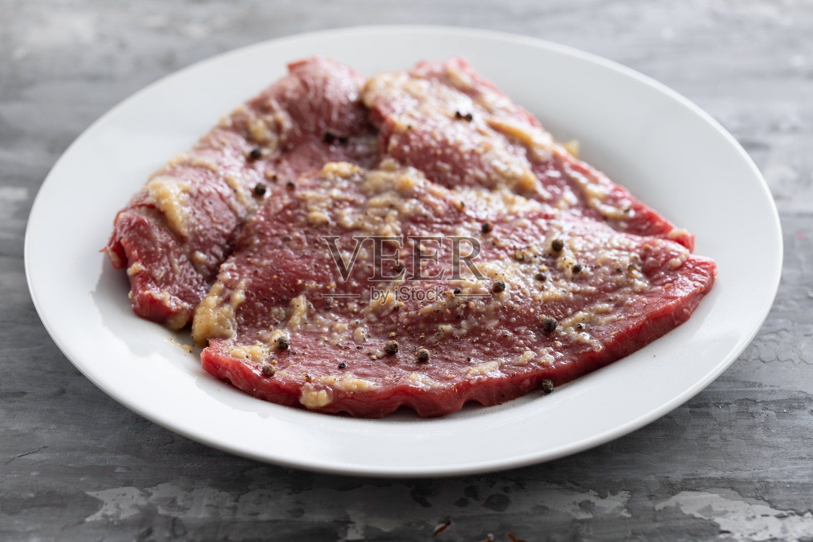 白色餐盘上的香料生肉照片摄影图片