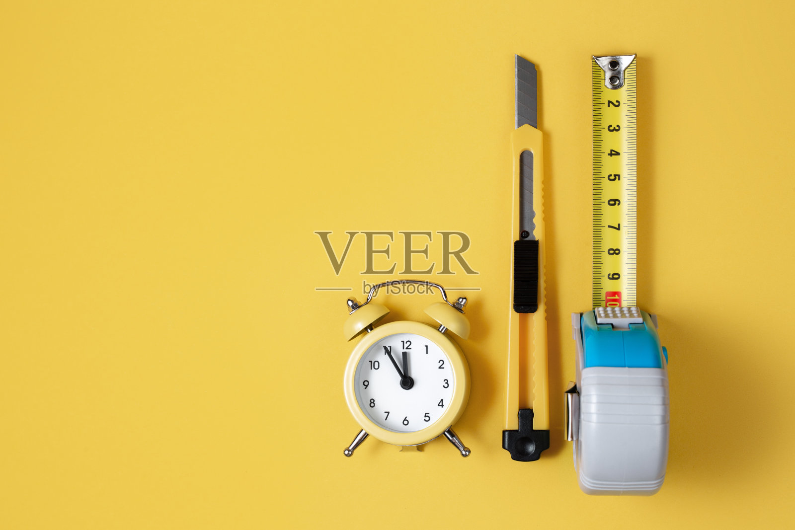 卷尺，切刀和时钟隔离在黄色背景上。木匠和建造概念。照片摄影图片