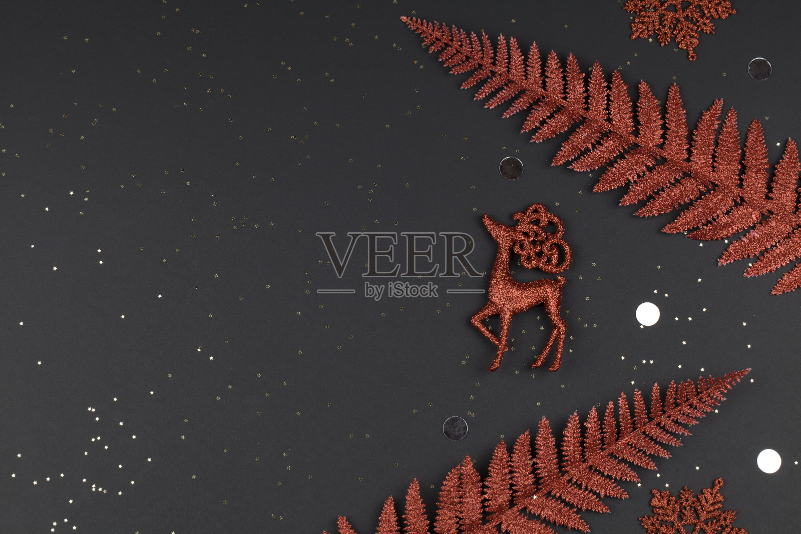 圣诞节或冬天的作文。红色的雪花，鹿和树枝在黑色的背景。照片摄影图片