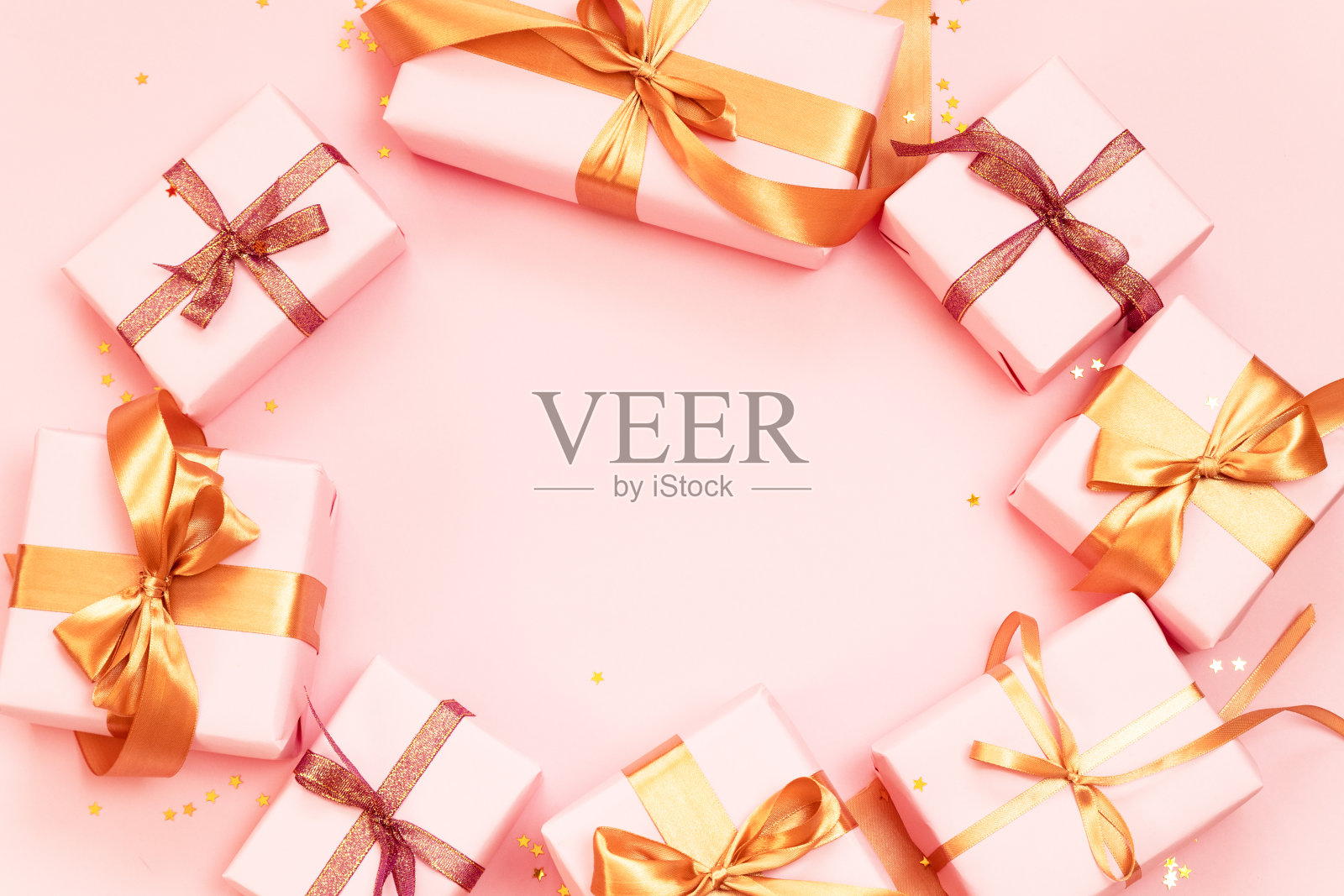 装饰框架与意想不到的礼物与金色蝴蝶结在粉红色的背景与复制空间。照片摄影图片