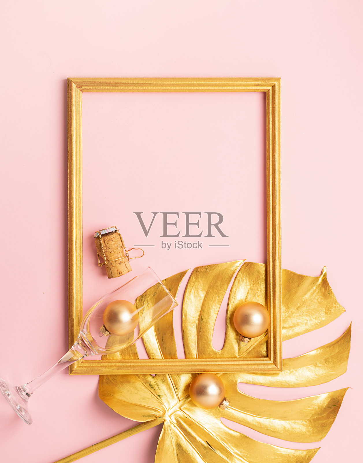 圣诞玩具空玻璃片热带植物蛇纹石软木香槟金色在粉红色的背景。照片摄影图片