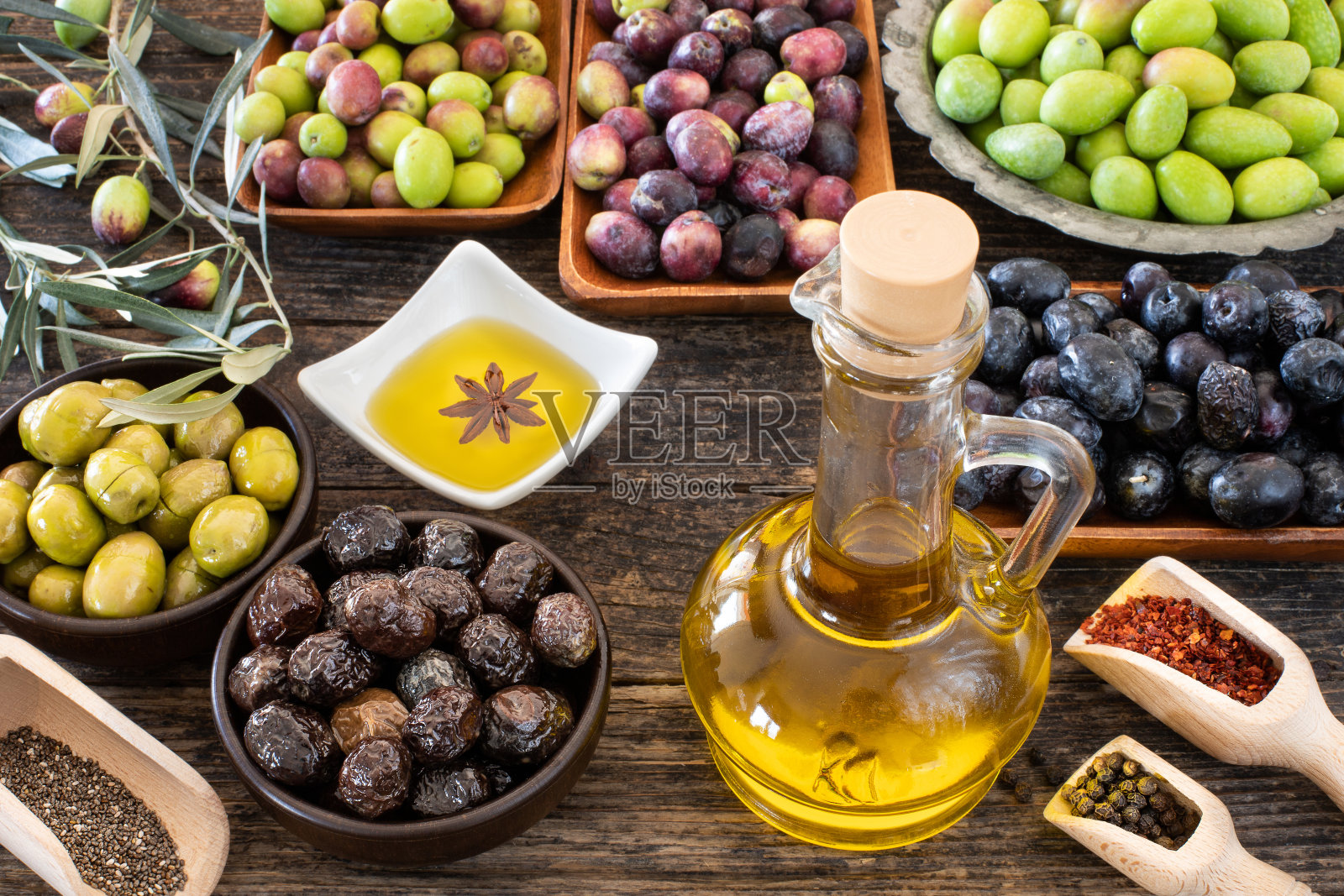 许多类型的橄榄，如绿色和黑色和橄榄油在质朴的木桌照片摄影图片