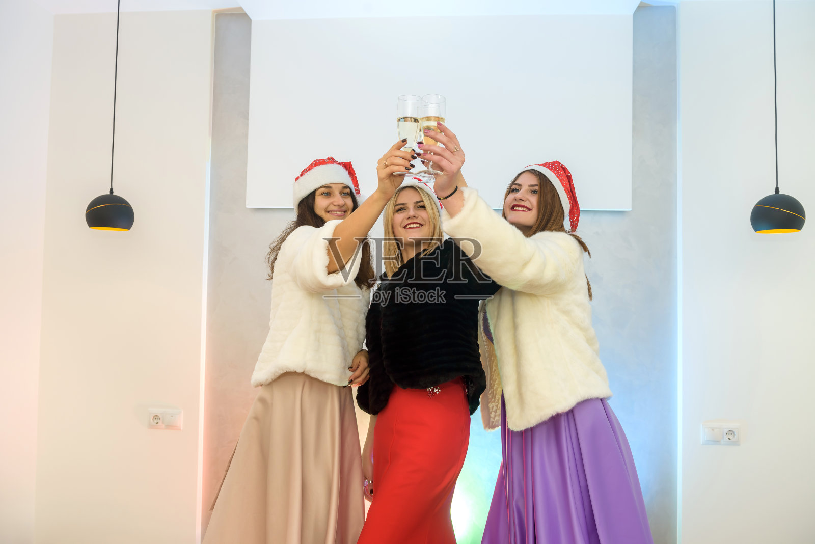 三个漂亮的女人拿着香槟杯在派对上祝酒。新年的庆祝活动照片摄影图片