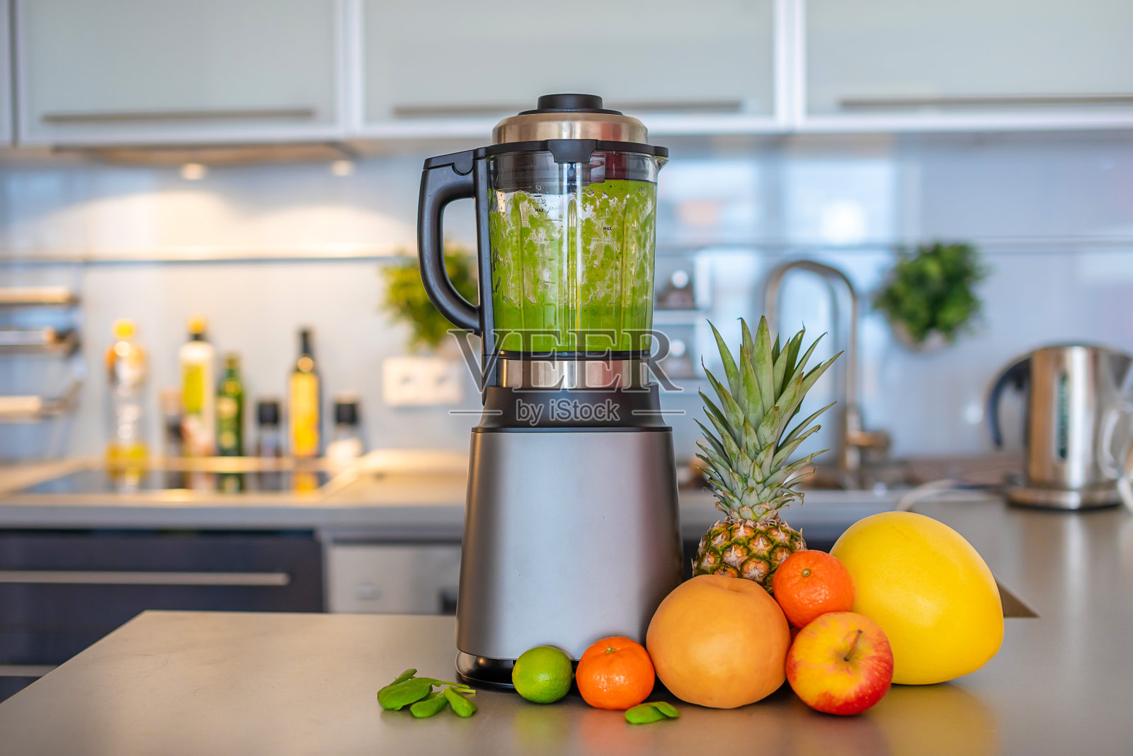 在家庭厨房用搅拌机制作绿色果汁，健康饮食生活理念照片摄影图片