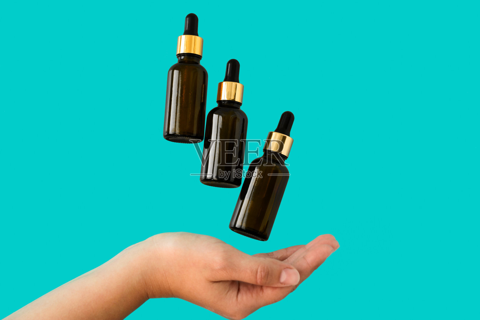 蓝色背景下，漂浮在女性手中的化妆品瓶照片摄影图片