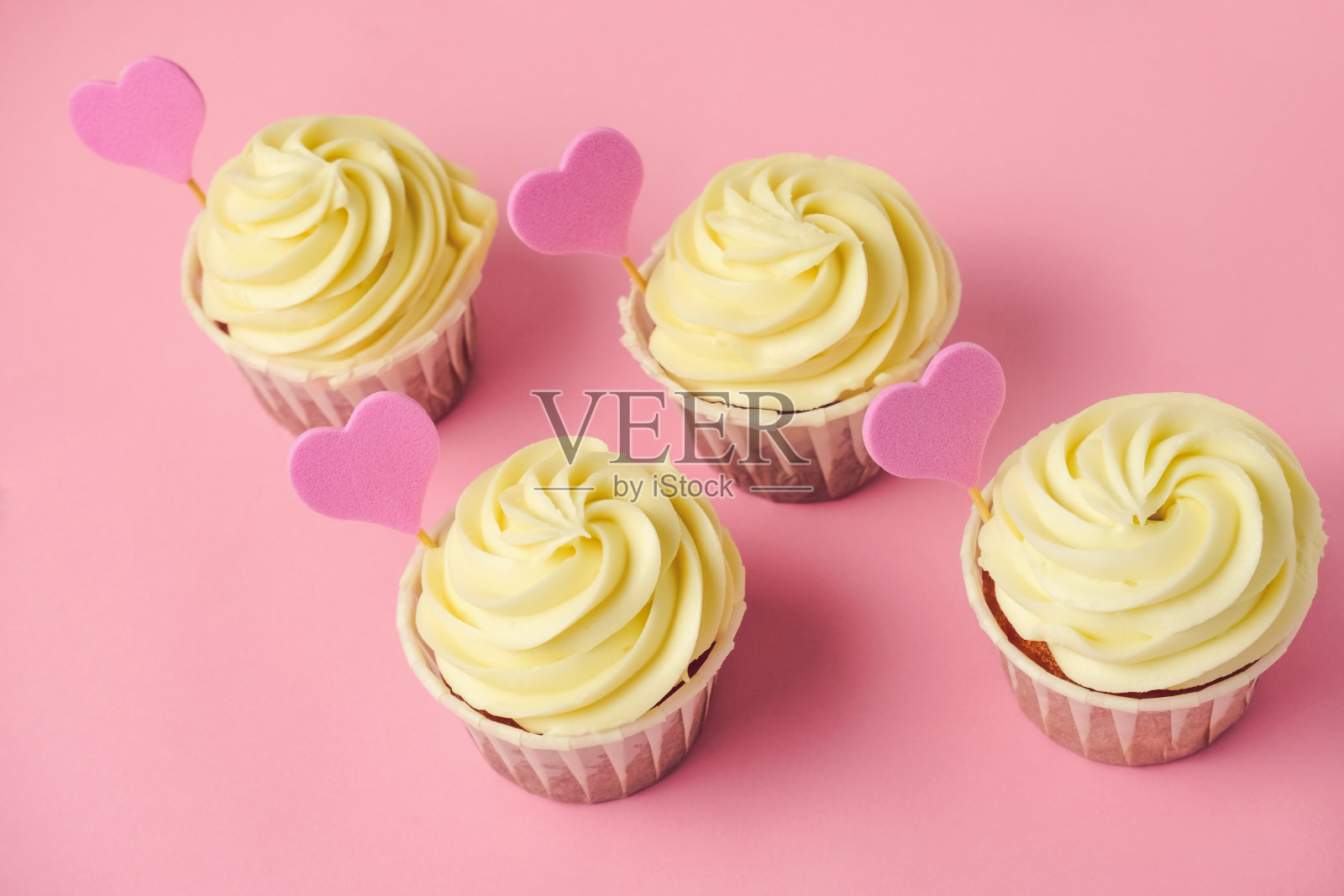 粉色爱心装饰的杯子蛋糕，淡粉色背景照片摄影图片