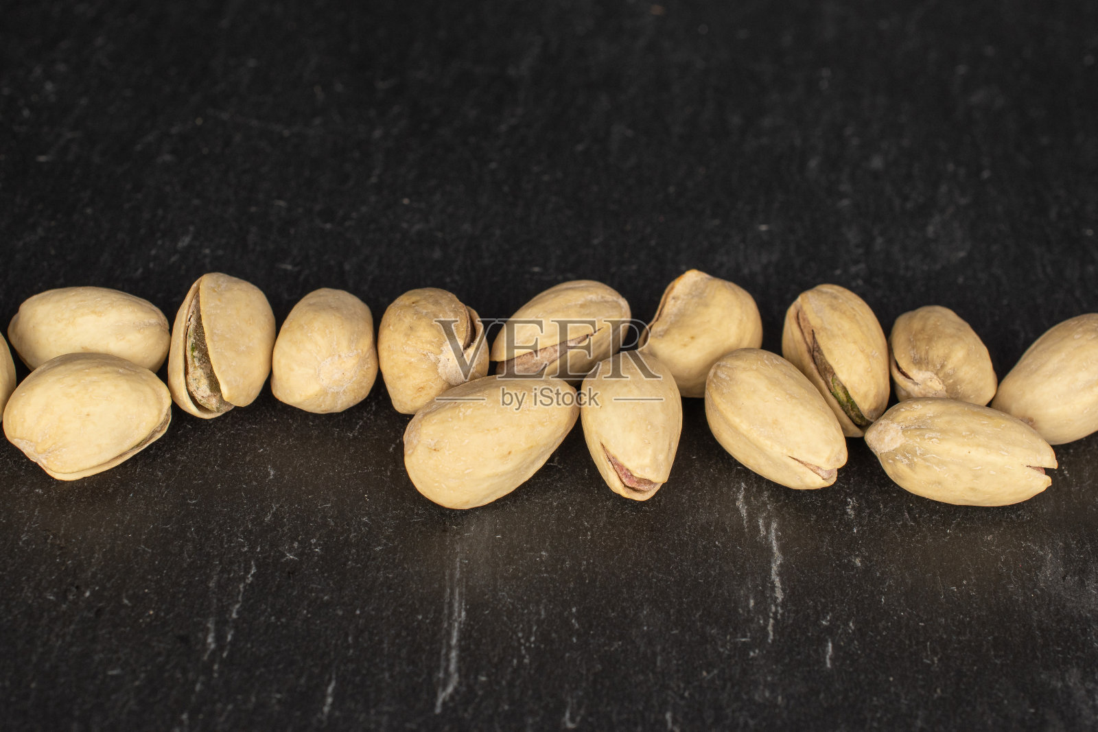 灰色的石头上加了盐的开心果照片摄影图片