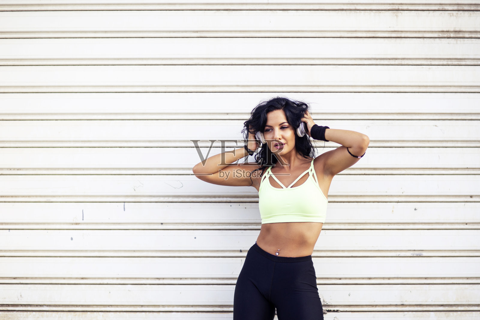 一个长黑发的健身女孩站在门前，头上戴着耳机照片摄影图片