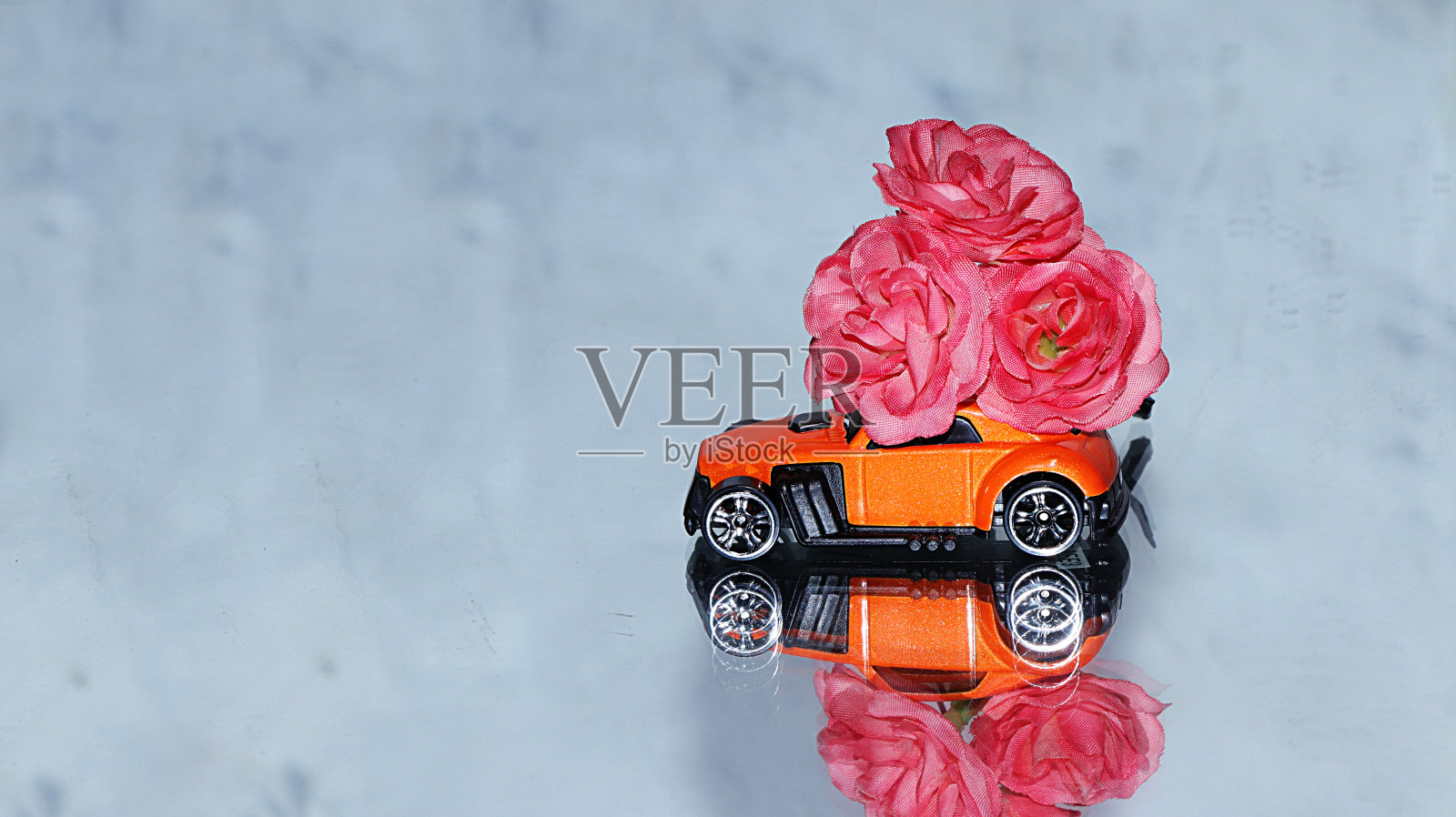 灰色镜面背景上有一大束花的红色玩具车。祝贺你的生日，节日，情人节，圣诞快乐，照片摄影图片