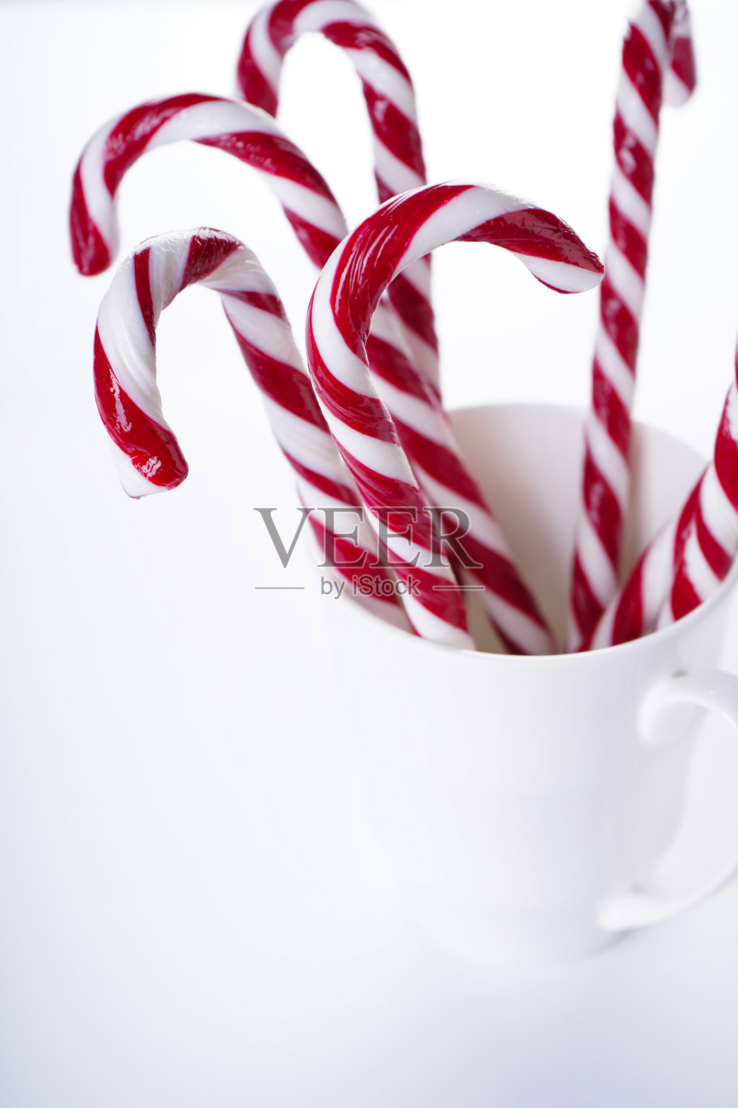 圣诞糖果在白色的陶瓷杯，在白色的背景。关闭了。照片摄影图片