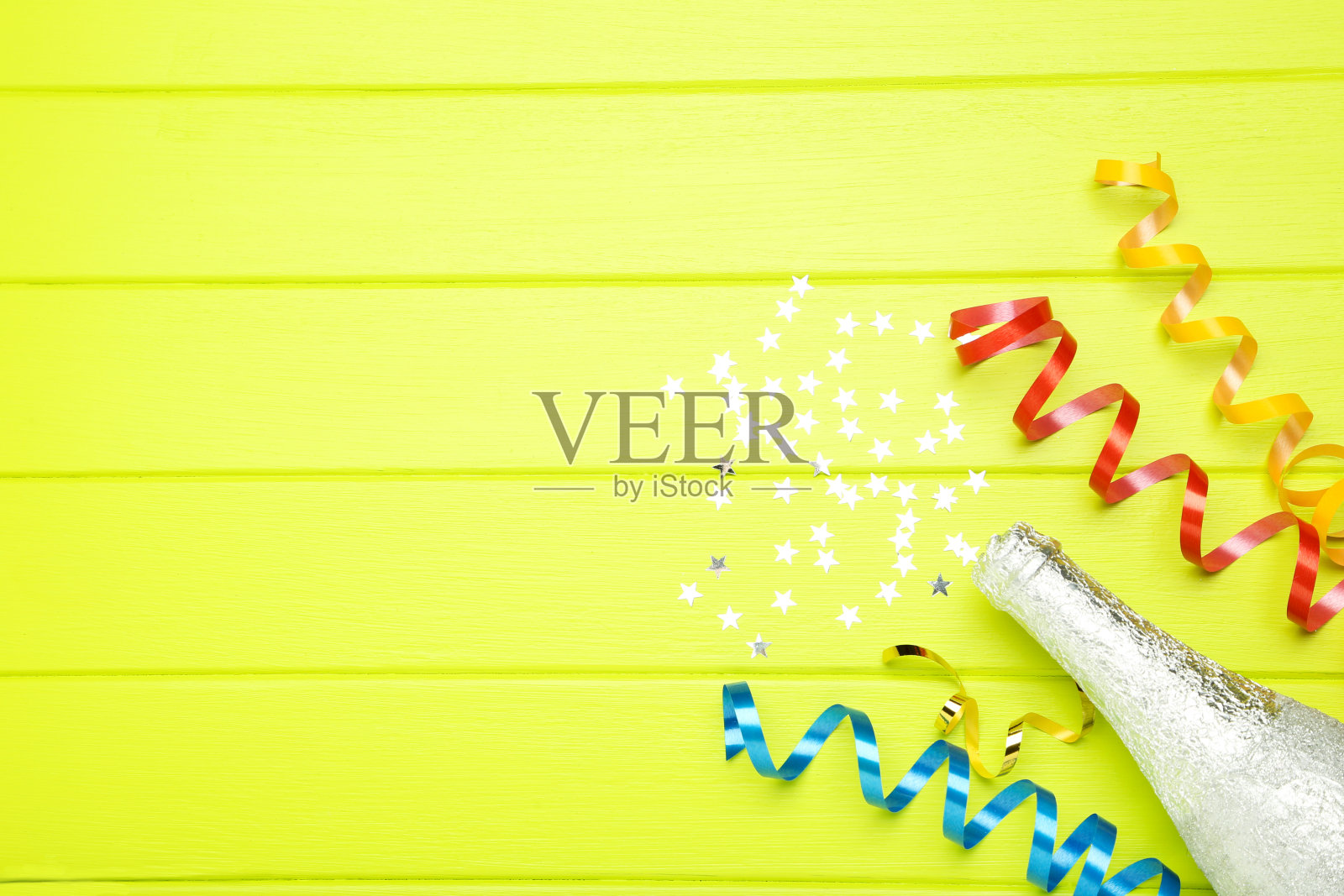 绿色木质背景上的星星彩带和香槟瓶照片摄影图片