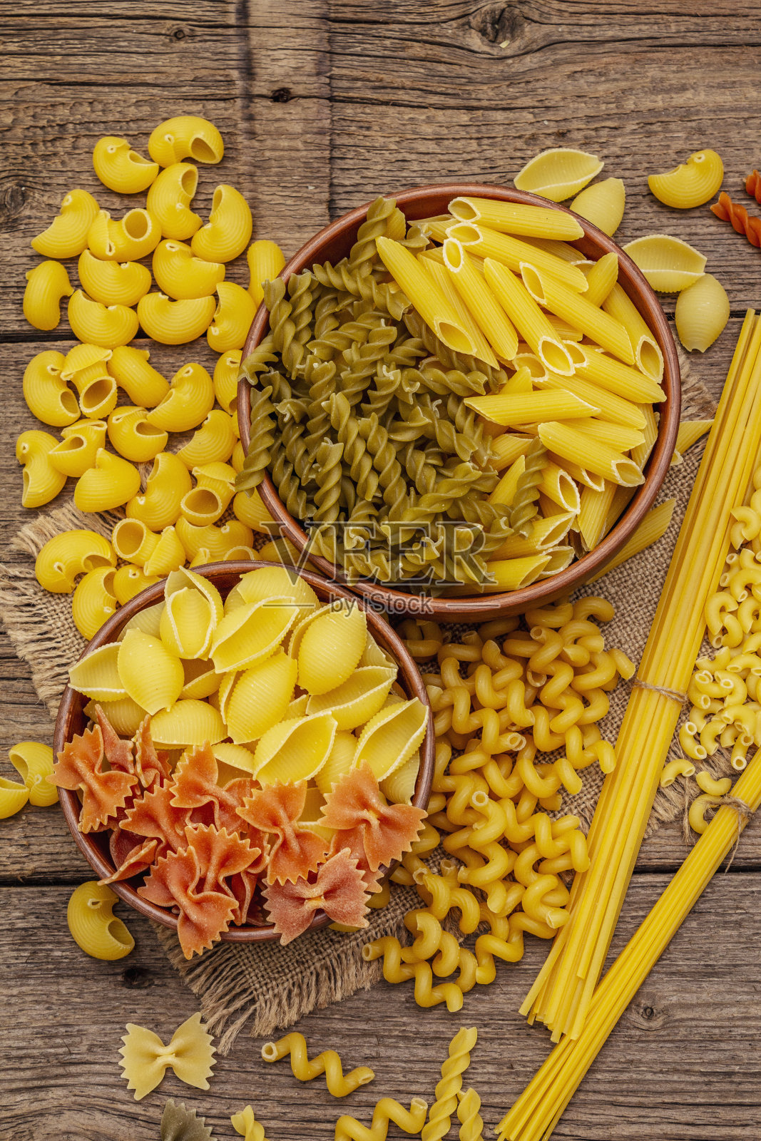 陶瓷碗里装着不同种类的意大利面。传统的意大利食品，健康的饮食理念。乡村木桌照片摄影图片