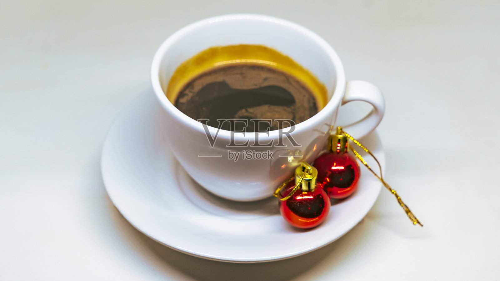 白热咖啡，两个圣诞树玩具和金属箔。白色背景下的圣诞饮品概念。照片摄影图片