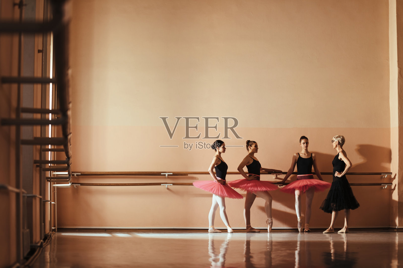 一群芭蕾舞演员在舞蹈工作室与他们的芭蕾舞教练交谈。照片摄影图片