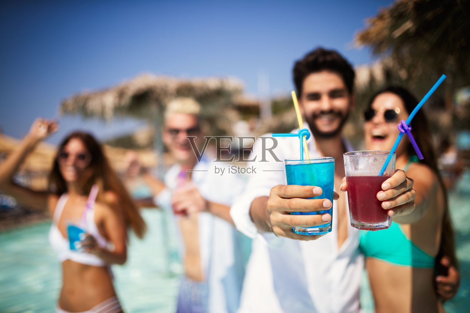 夏季聚会。朋友们在海滩上喝着鸡尾酒，玩得很开心照片摄影图片