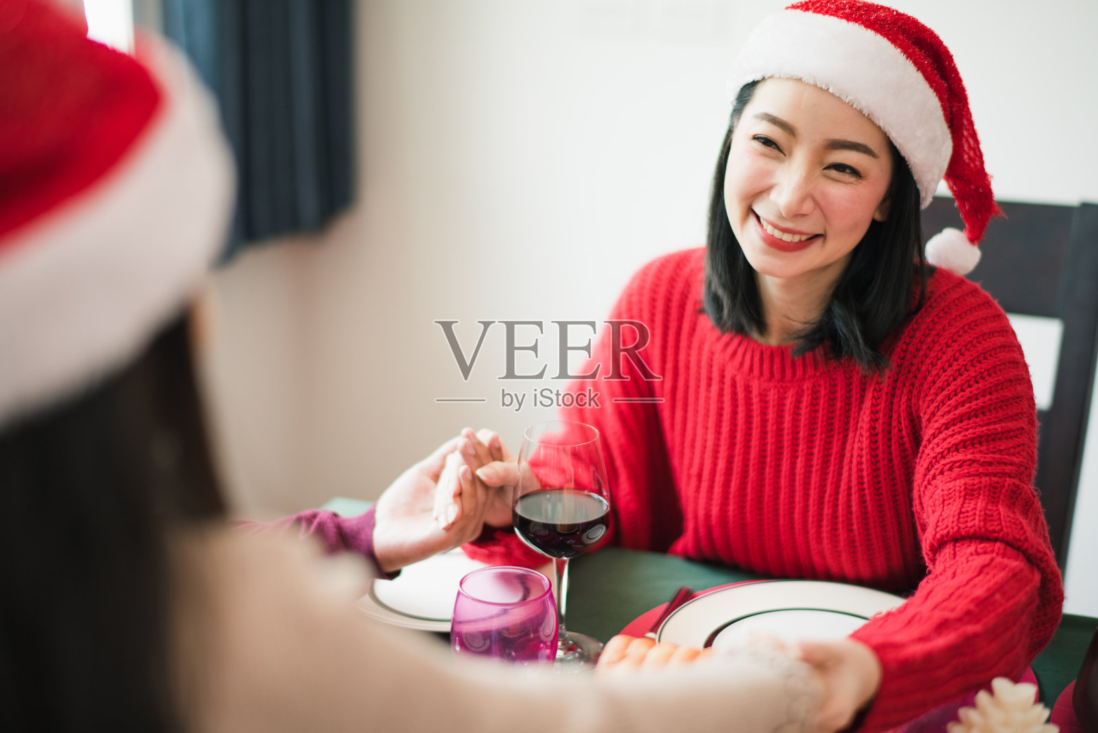 年轻的亚洲家庭在圣诞节庆祝，父母和女儿在厨房的早餐前祈祷和触摸手。感受爱和快乐。圣诞快乐。照片摄影图片