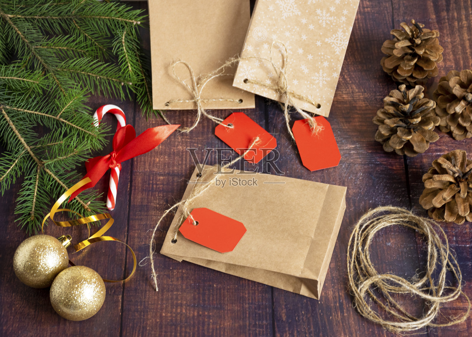 圣诞风格的木制背景手工牛皮纸制作的礼品袋，装饰有圣诞树球，锥，绳球，冷杉树枝。圣诞节，新年，寒假。照片摄影图片