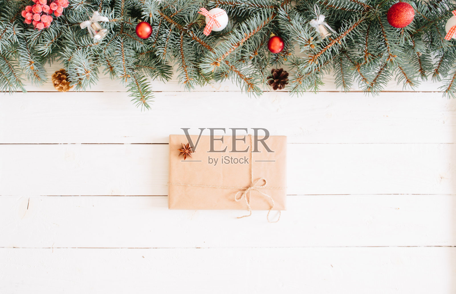 木制桌子上放着圣诞礼盒和冷杉树枝。顶部视图与复制空间。圣诞背景，用冷杉树枝，仙女灯，礼物盒和圣诞装饰在白色的木板上照片摄影图片