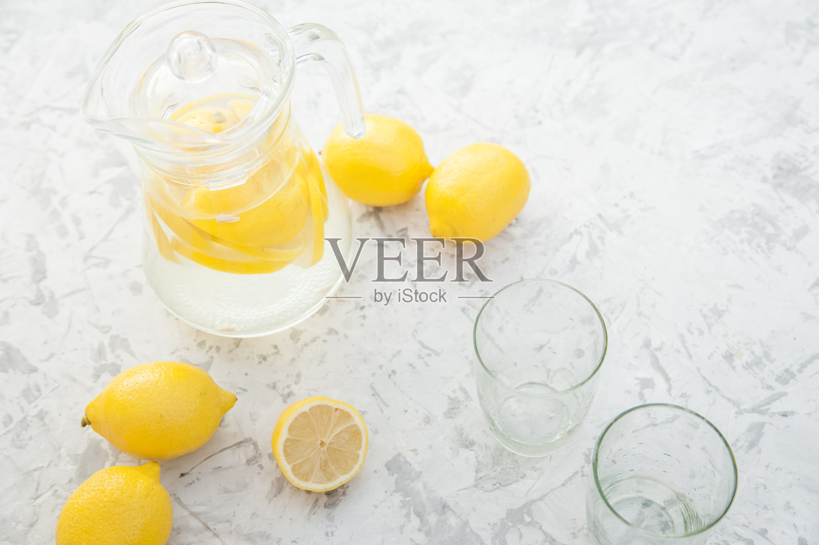 在灯光背景上自制柠檬水的概念。柠檬，玻璃杯，薄荷，水壶和复印空间。夏日清凉饮料柠檬水。照片摄影图片