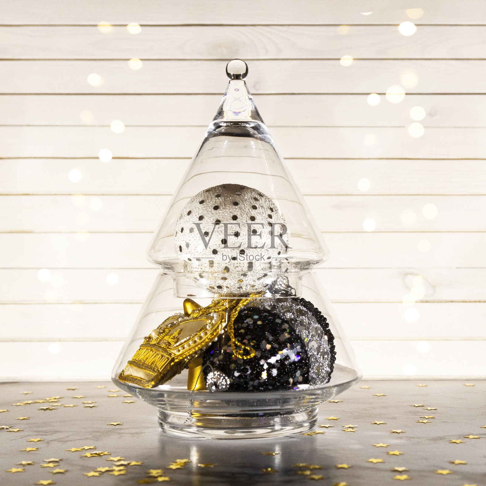 圣诞装饰——玻璃圣诞树，上面有金色、白色和黑色的球、小装饰品和玩具，以新年为背景。创意贺卡的趋势颜色，复制空间照片摄影图片