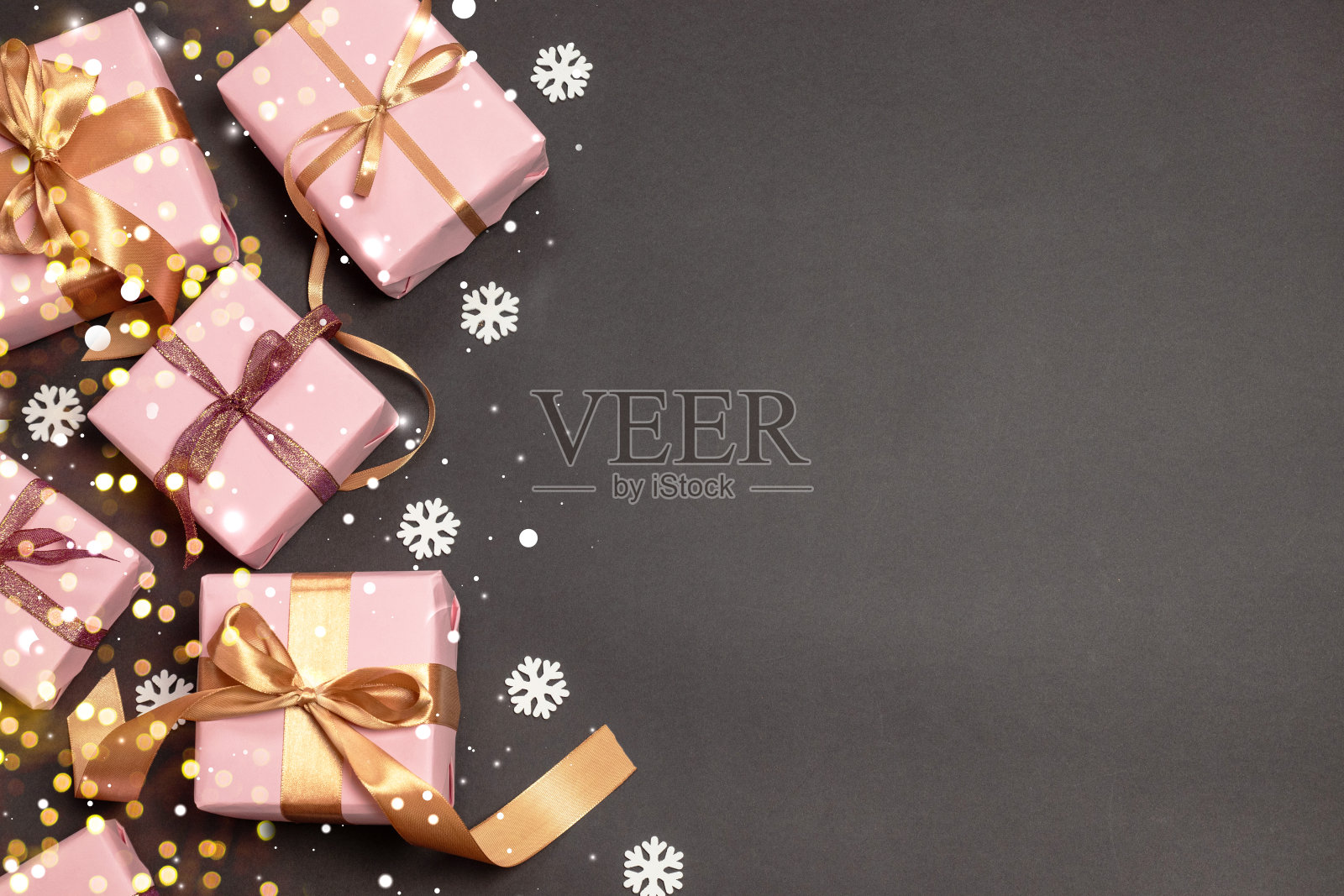 圣诞快乐和节日快乐图案与惊喜礼物，金色图册丝带和雪在黑暗的背景。照片摄影图片