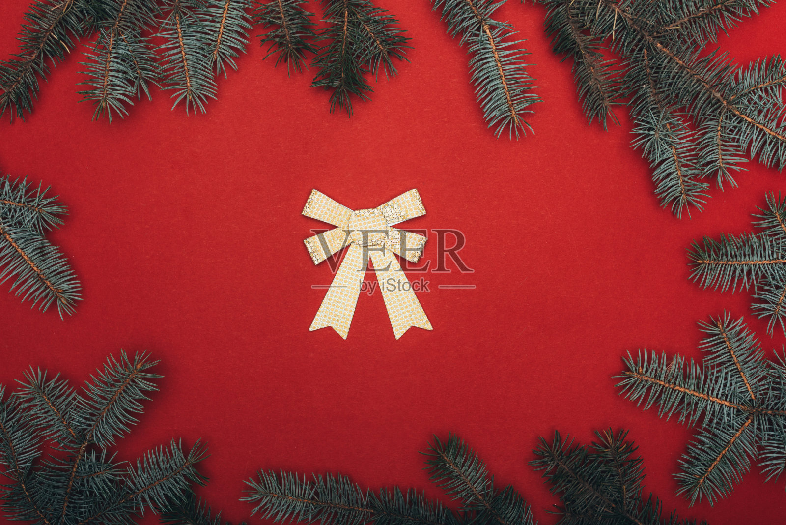 顶视图的圣诞框架云杉树枝和金色的弓在红色照片摄影图片